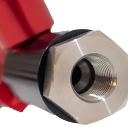 Close-up of a stainless steel bushing fitting with threaded connection on a red valve body