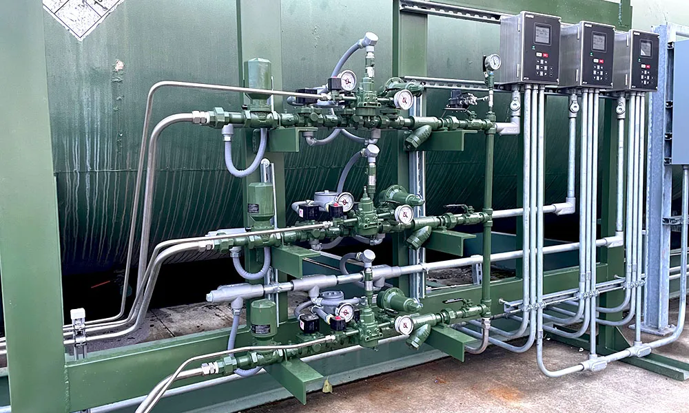 Close-up of the gas train and control piping with pressure gauges, regulators, valves, and three mounted Profire controllers above the manifold.