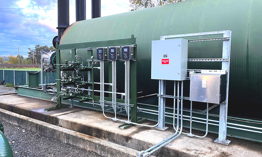 Side view of the unit showing a pipe rack with multiple controllers, tubing and valves, and adjacent electrical enclosures on a galvanized frame.
