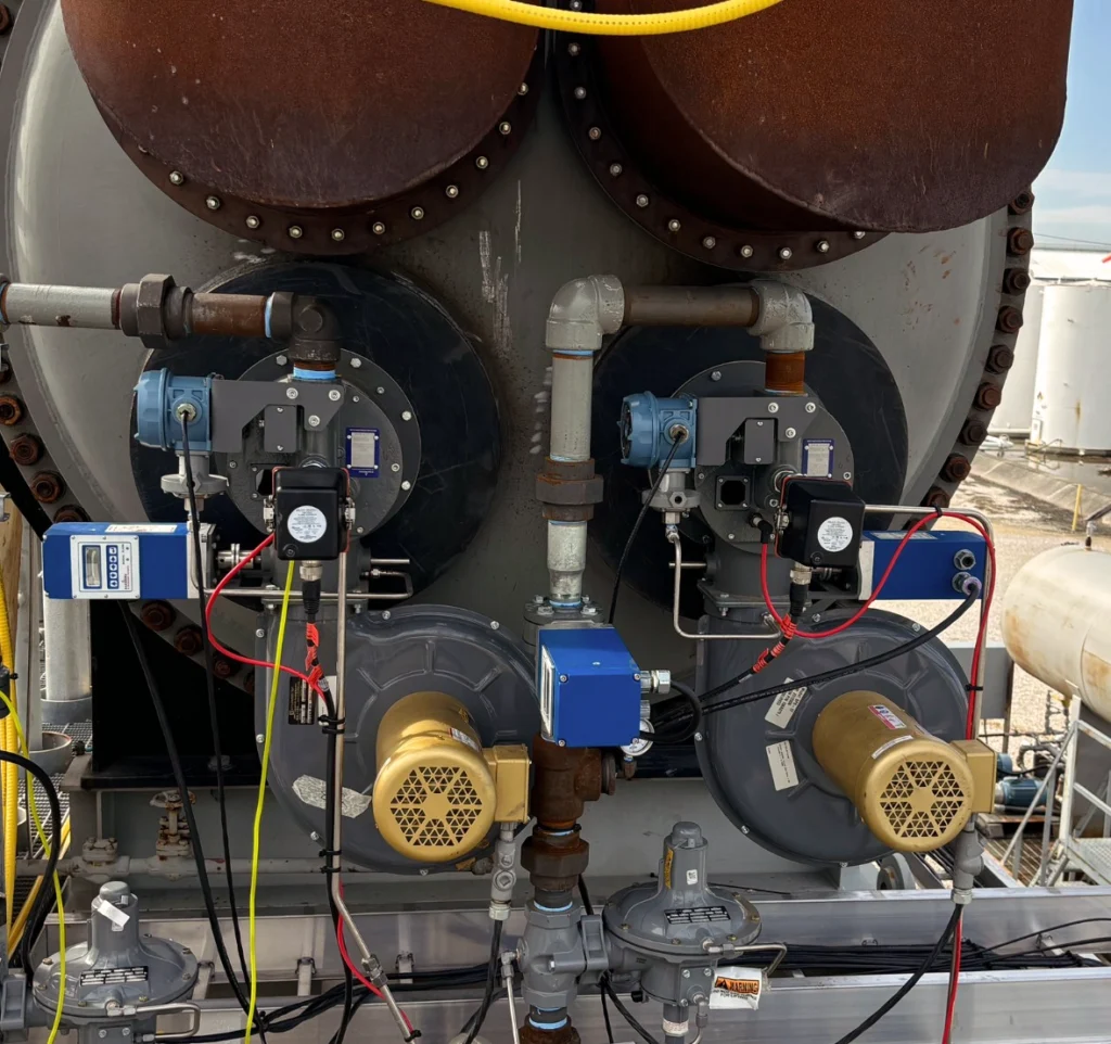 Front view of a dual-burner combustion system with Fireye flame scanners, motors, regulators, piping, and control wiring mounted on a process vessel.