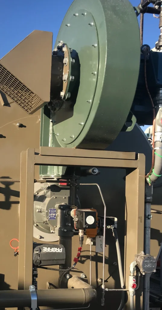 Side view of an industrial burner with a Fireye flame scanner mounted below a large green air housing, with associated piping and instrumentation.