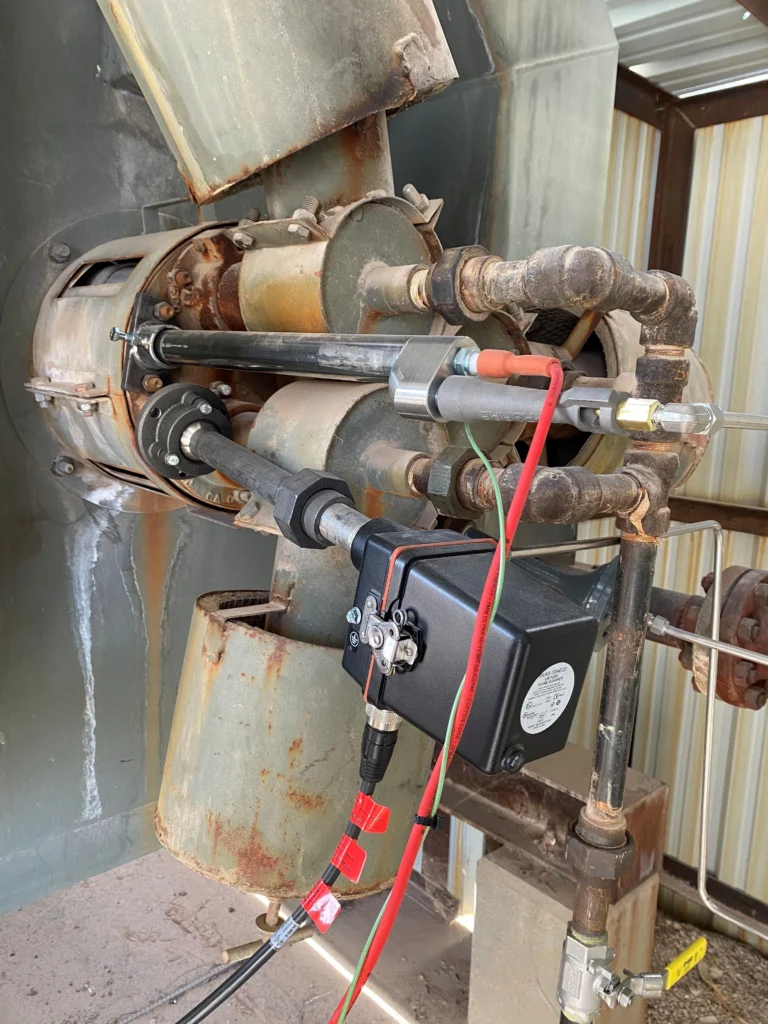 Close-up of a Fireye flame scanner mounted on a weathered burner assembly with metal piping, ignition components, and field wiring.