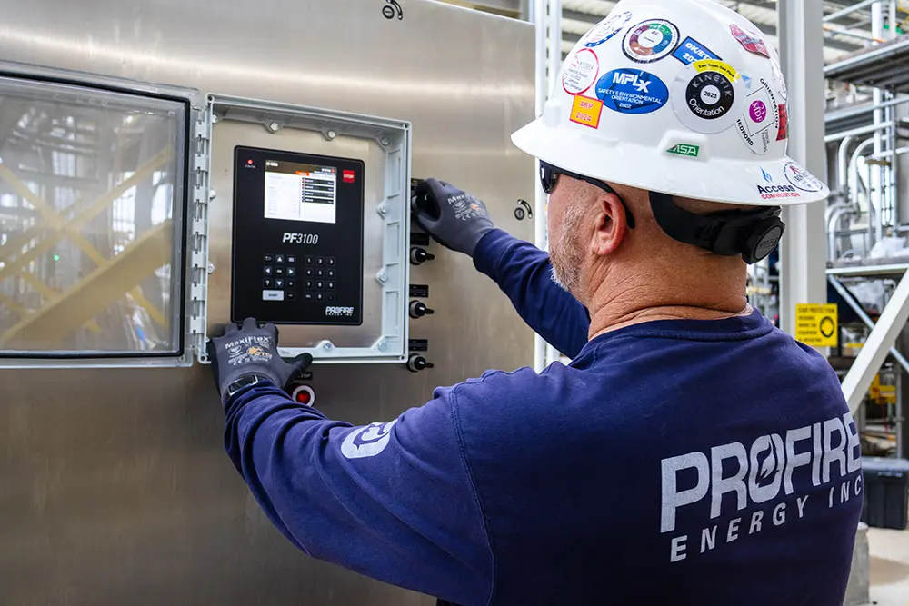 Technician operating a Profire PF3100 burner management controller on industrial equipment.