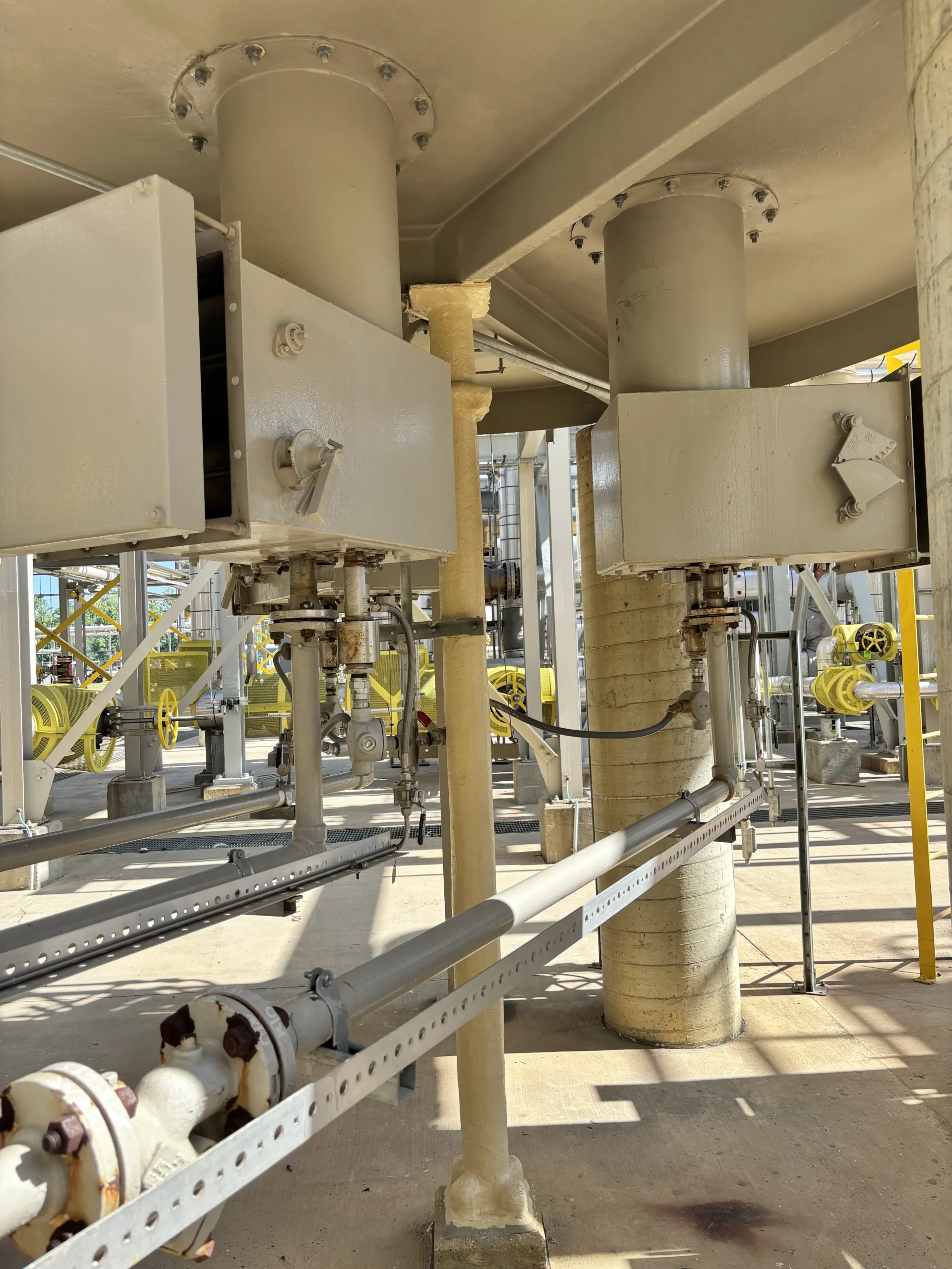 Burner assemblies and fuel piping installed beneath an industrial process heater, with access panels, flanged connections, and structural supports visible.