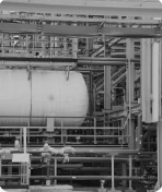 A picture of a heated tank and pipes at a refinery