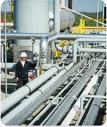 A natural gas utility worker with safety equipment inspects plant equipment