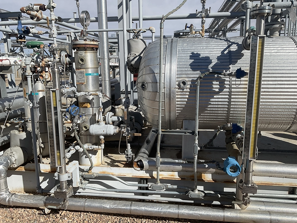 Insulated glycol reboiler and process equipment surrounded by piping, valves, and level indicators.