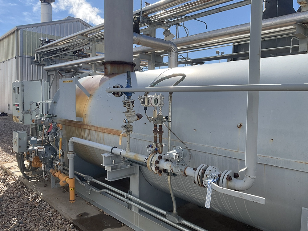 Side view of an industrial heater with process piping, instrumentation, valves, and control panels.