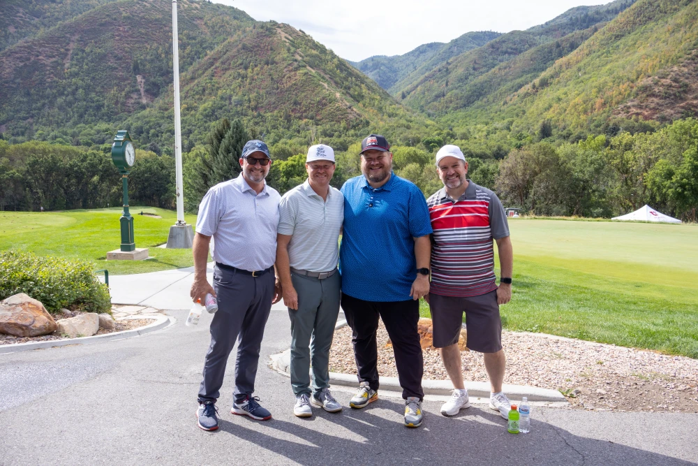 Four golf tournament participants posing on a mountain golf course during the PROFIRE Burn Camp fundraising event.