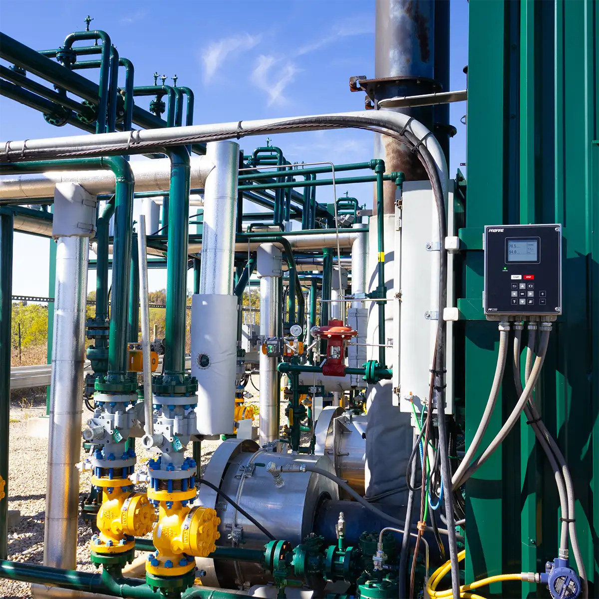 Profire controller mounted on a green building at an oil and gas wellsite with valves and piping
